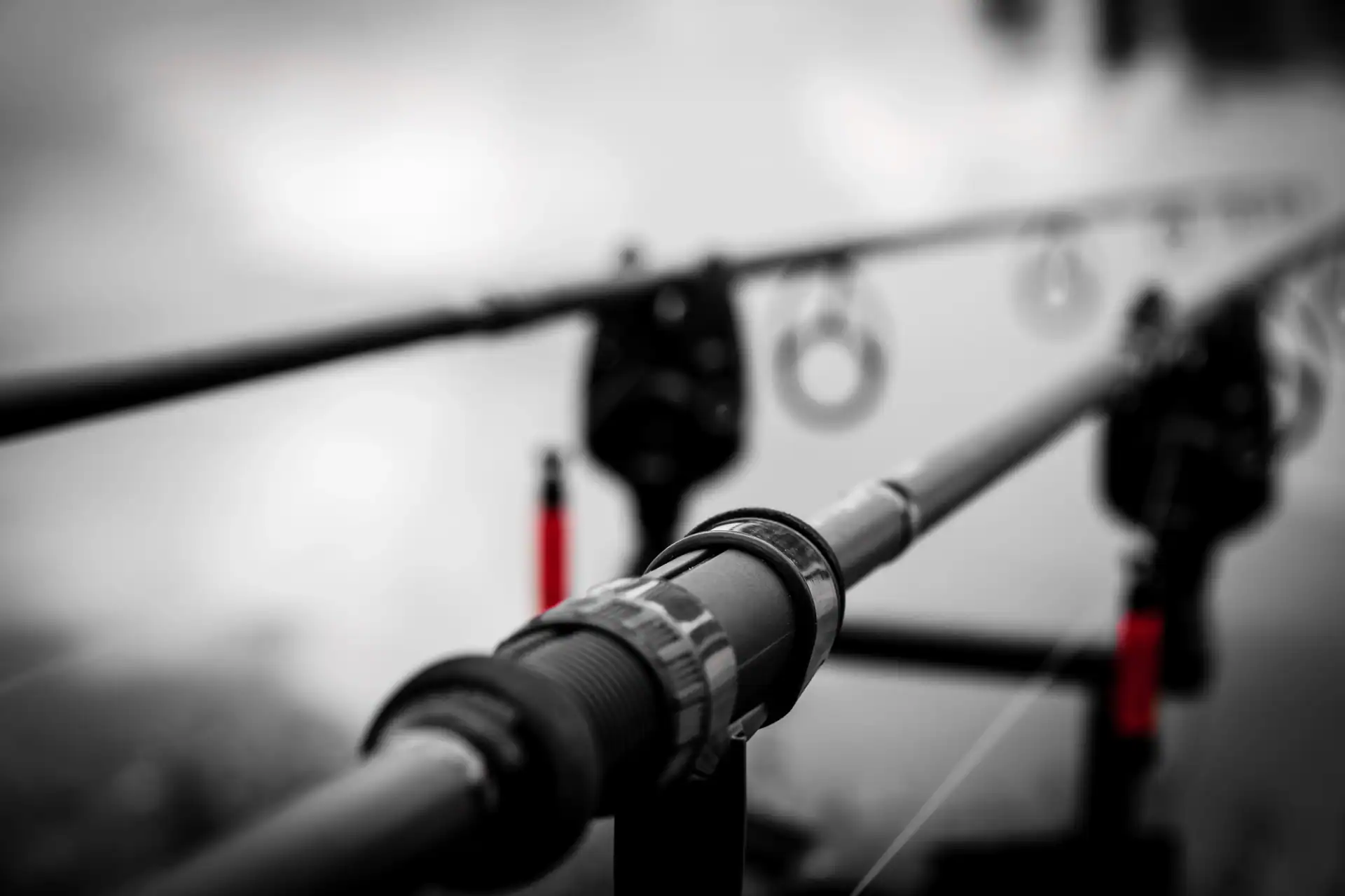 Close-up view of fishing rods set up on a rod holder, with the focus on the reel seat and a blurred background.
